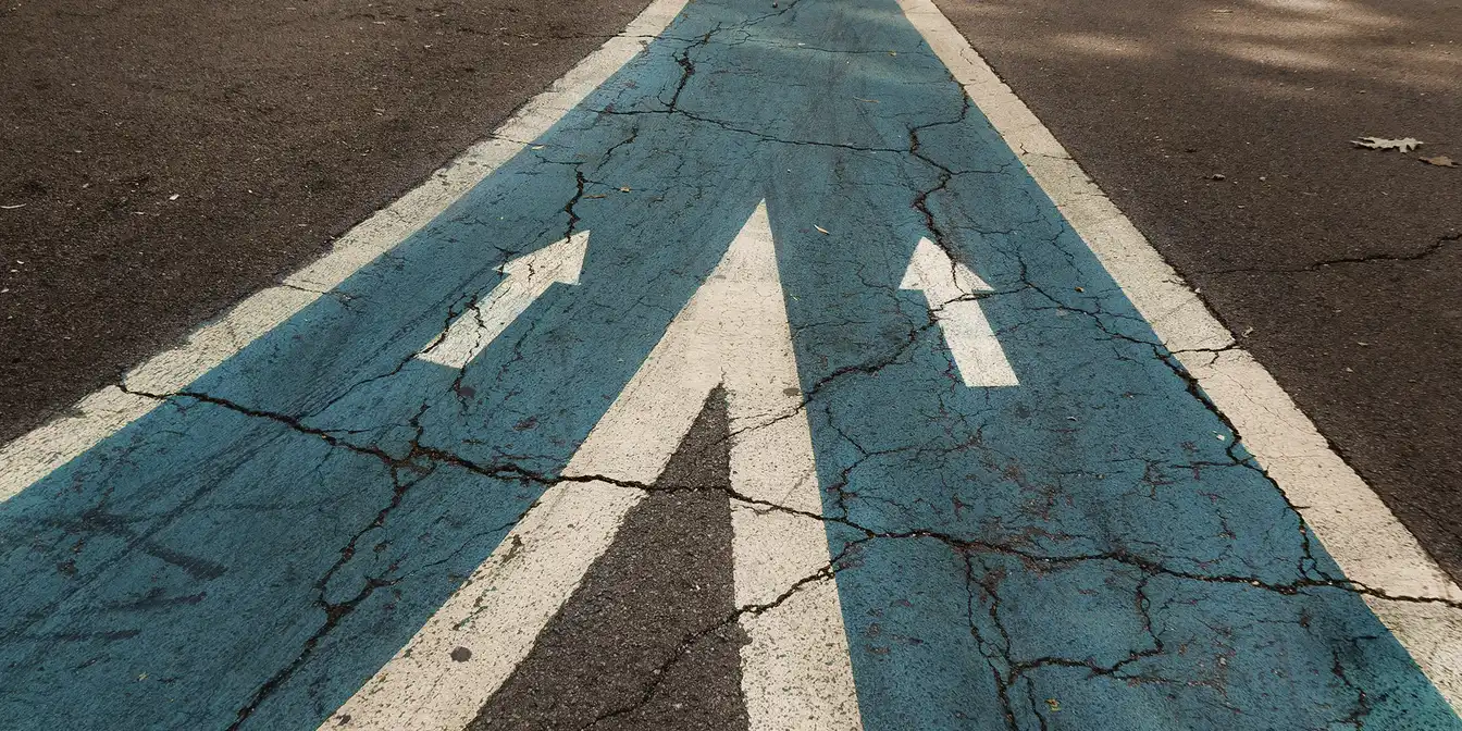 Straße mit zwei Pfeilwegen die zusammenführen zu einem Weg 